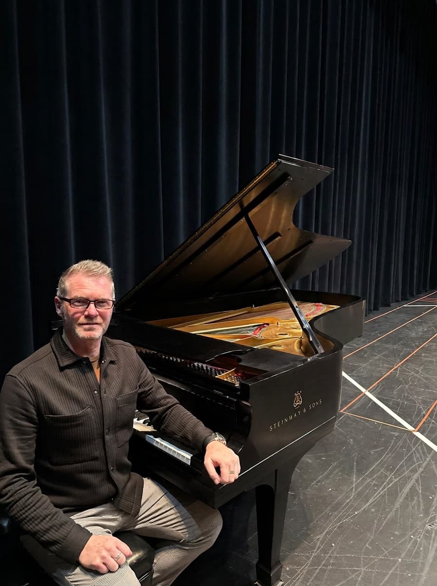 Craig Ralston aan een Steinway-vleugel op het podium, voor een donker toneeldoek